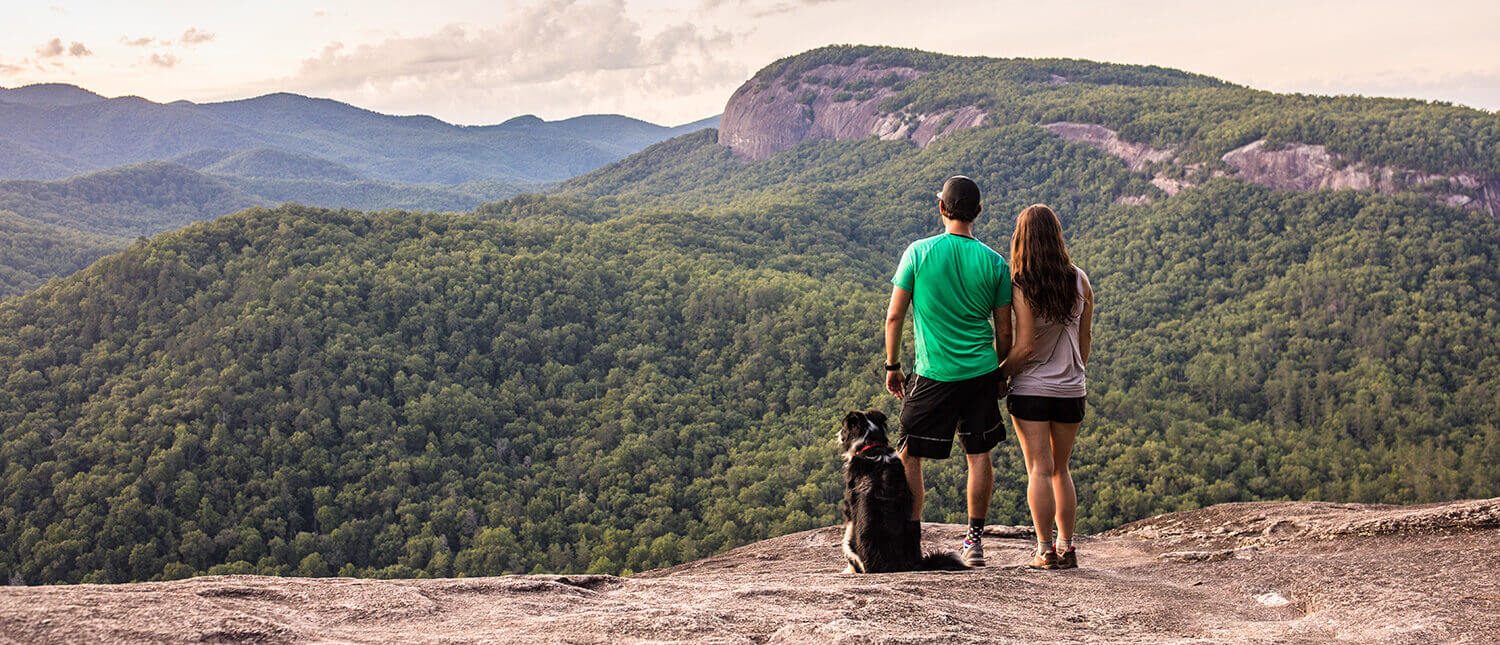 Couple with a dog standing on John Rock taking in a scenic vista in Pisgah National Forest